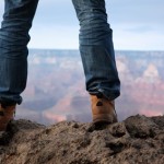 Male feet in hiking boots standing on edge of a cliff
