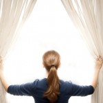 A young woman opening window curtains. A young woman opening window curtains.